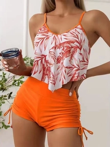 Detail of high waisted orange bikini bottoms with side drawstring and tropical leaf print top