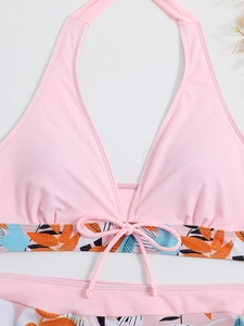 Dettaglio del top bikini halter rosa con stampa di palme tropicali e fiocco frontale
