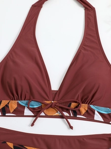 Dettaglio del top bikini bordeaux a fascia con stampa tropicale e fiocco di perle