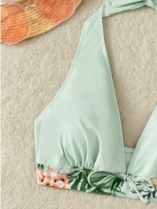 Dettaglio del top bikini halter verde chiaro con stampa floreale arancione e lacci