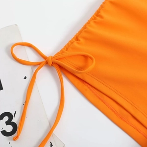 Detail view of bright orange bikini with adjustable side drawstrings and bow tie design