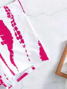 Macro shot of high-waisted tie-dye bikini bottoms in white and pink on a grey surface