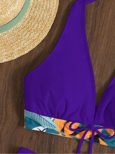 Dettaglio del top bikini viola a fascia con motivo tropicale su legno scuro