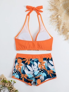 Dettaglio del top bikini arancione con fiocco e pantaloncini a stampa tropicale