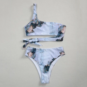 Flat lay detail of one-shoulder bikini with blue marble print and waist bow tie decoration