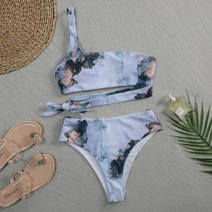 Flat lay of marble print one-shoulder bikini with high-waist bottom and tie-waist detail