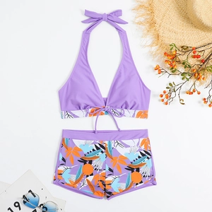 Dettaglio del top bikini floreale e pantaloncini da bagno a vita alta con accessori estivi