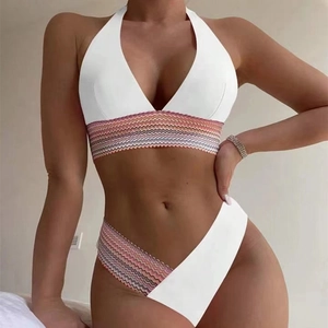 Detail eines weißen Bikinis mit buntem Wellensaum und Neckholder-Design am Model