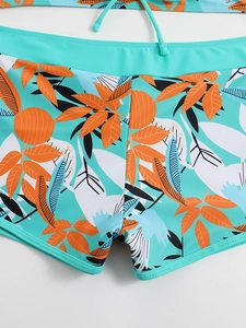 Dettaglio dei pantaloncini da bagno verde menta con stampe tropicali arancioni e cuciture