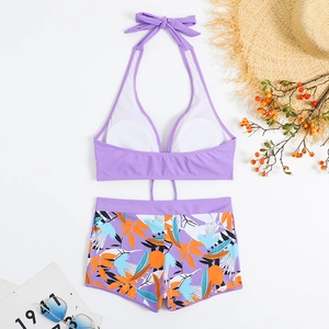 Top bikini viola a lupetto e slip a fiori con accessori estivi su superficie piana