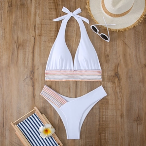 Flachbild eines weißen Halter-Bikinis mit bunten Wellen-Gummibändern auf Holzgrund