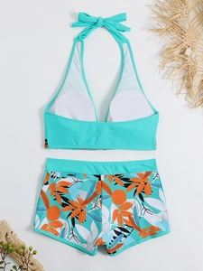 Dettaglio del bikini a fascia verde menta con pantaloncini con stampa tropicale