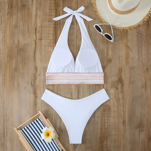 Flachbild des weißen zweiteiligen Bikinis mit bunter Wellenstickerei auf Holzgrund
