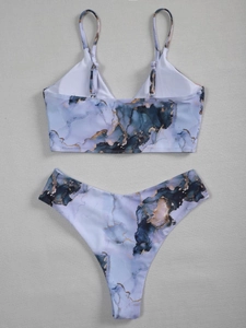 Detailed flat lay of blue marble print bikini with gold sand textures and V-neck top