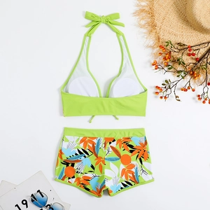 Top bikini a fascia verde e slip a pantaloncino floreale con accessori da spiaggia estivi