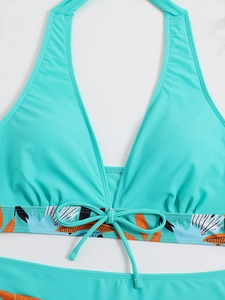 Dettaglio del top bikini turchese con stampa tropicale e ciondolo a perla centrale