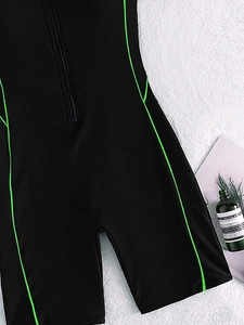 Detailed view of the front zipper and neon green contrast stitching on black swimwear