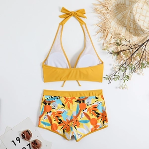 Dettaglio del bikini giallo a fascia e dei pantaloncini da bagno con stampa tropicale