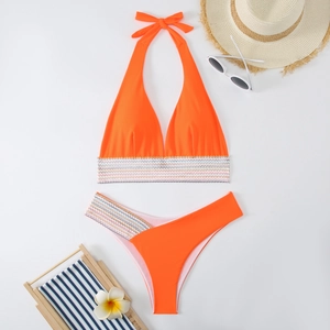 Flachbild des leuchtend orangen Bikinis mit gewebten Dekobändern und Strandaccessoires
