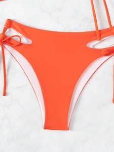 Detail of bright orange high-waisted bikini bottoms with side cutouts and tie-up strings