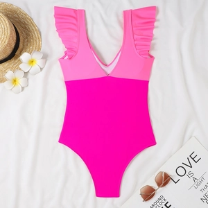 Close-up of pink V-neck swimsuit with ruffled sleeves on a beach vacation layout