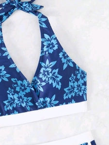 Detail eines blauen Bikini-Tops mit tropischem Hibiskus-Print und weißem Gummiband-Saum