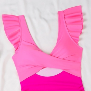 Detail of pink color-block swimsuit featuring ruffled shoulders and a cross-front cutout