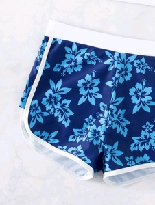 Detail der High-Waist Badeshorts mit blauem Hibiskus-Blumenprint und weißen Seitenpaspeln