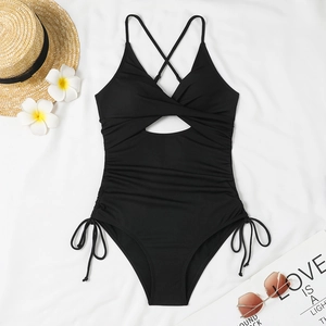 Flat lay of ribbed black one-piece swimsuit with cross straps and side drawstring details