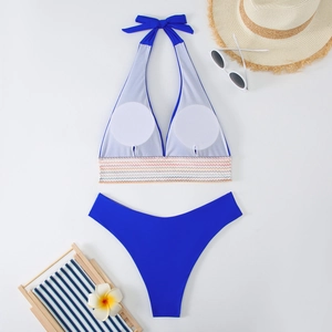 Flachbild von blauem Bikini mit bunten Gummibändern, Strohhut und Stranddekorationen