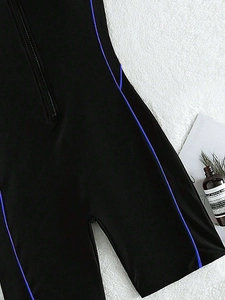 Detailed macro view of the front zipper and blue stitching on the black athletic swimsuit