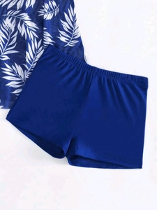 Detailed view of the dark blue tropical leaf print and elastic fabric on this tankini set