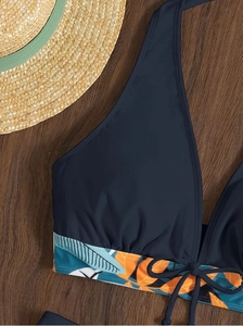 Dettaglio del top bikini a fascia blu navy con stampa tropicale e coulisse sul davanti