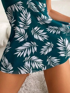 Close-up of dark green tankini fabric with white tropical leaf prints and soft textures