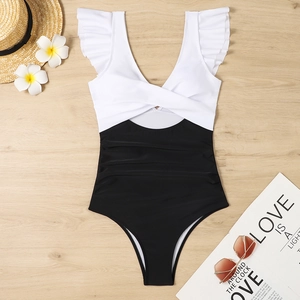 Flat lay view of a color block one piece swimsuit with ruffle straps on wood background