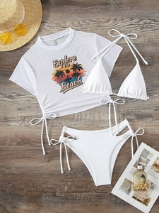 Flat lay of white 3-piece bikini set with sheer mesh cover-up and beach print on wood floor