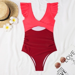 Detailed flat lay of a pink and burgundy swimsuit with ruffles and side waist cut-out
