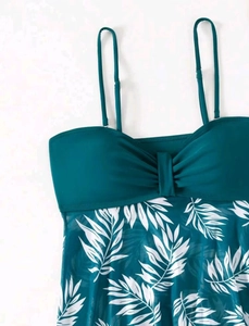 Detail of teal tankini top with bow-knot pleats and white tropical leaf mesh overlay