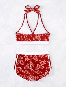 Detailansicht eines burgunderroten Bikinis mit tropischem Blumenmuster und weißer Paspelierung