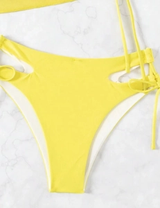Detail of high-waisted yellow bikini bottom featuring side cut-outs and lace-up strap