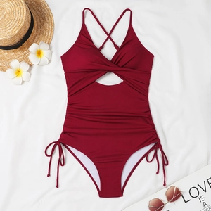 Flat lay of burgundy ribbed one-piece swimsuit with front cutout and drawstring side details
