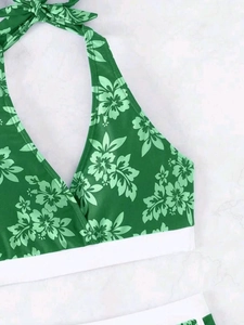 Detail eines grünen Bikini-Oberteils mit Tropenprint und weißem elastischem Unterband