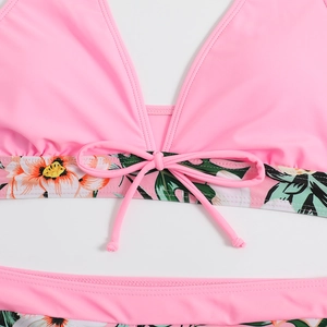 Dettaglio bikini rosa a fiori tropicali con scollo a V profondo e fiocco frontale