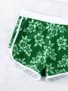 Detail der High Waist Schwimmshorts mit grünem Blumenmuster und weißer Paspelierung