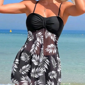 Women's black tankini swimdress with white leaf print and mesh skirt on beach