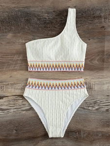 Detail of white one-shoulder bikini with colorful wave embroidery on high waist band