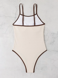 Detail of cream one-piece swimsuit featuring brown straps and 3D textured ripple fabric