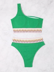 Flat lay of green one-shoulder bikini with colorful zigzag elastic bands on marble