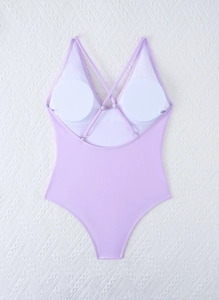 Detail of lavender one-piece swimsuit featuring crisscross back straps and metal buckles
