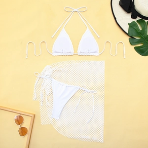 Close-up of white three-piece bikini with mesh skirt, sun hat, and beach accessories